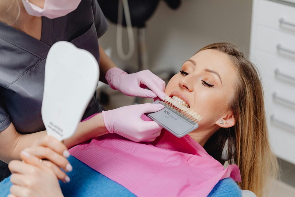 Dentist using a shade guide to match tooth color for a patient in a dental clinic.